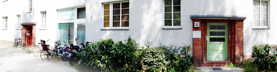 Die Praxis für Physiotherapie Oliver Grunow in der Wigandstaler Straße 32 in Berlin-Weißensee: Altbaufassade mit dem Praxisfenster links und der grünen Haustür Nummer 32 rechts